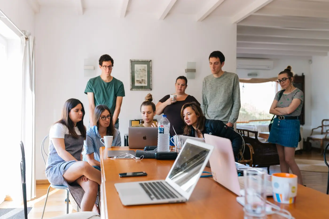 Students working together around a table with laptops